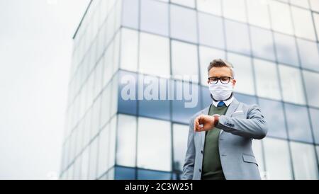 Low-angle view of businessman standing outdoors, wearing face mask at the airport. Stock Photo