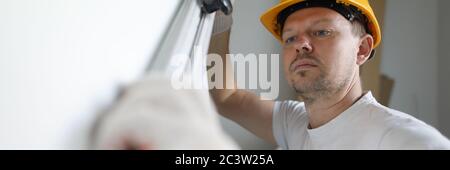 Builder helmet measures wall level with building Stock Photo