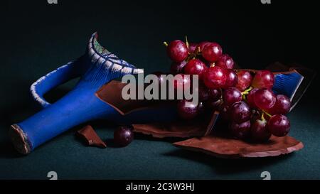 still life, bunch of grapes with a broken bottle of wine on a dark background Stock Photo
