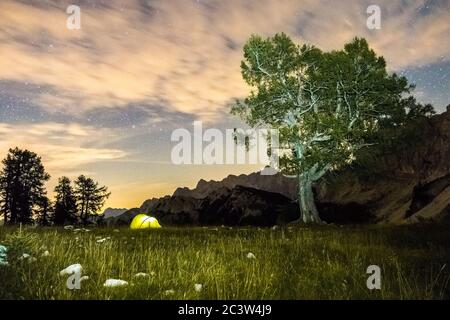 A tent glows under a star night sky at twilight hour. Julian Alps, Triglav National Park, Slovenia, Mountain Slemenova, Sleme. Stock Photo