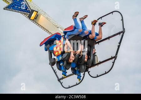 Youngsters upside-down on the Oxygen fairground ride at a funfair in the UK. Stock Photo