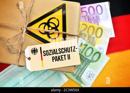 PHOTOMONTAGE, package Biogefährdungszeichen on Germany flag with tag and the label social protection package II, FOTOMONTAGE, Paket mit Biogefährdungs Stock Photo
