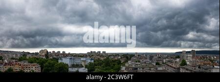 Panorama of dark thunderstorm sky hovering over Varna. Dramatic cloudscape over seaside city. Scenic stormy clouds on a summer day. Weather. Stock Photo