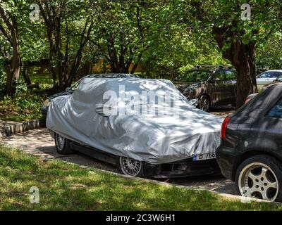Varna, Bulgaria, June 18, 2020. Silver weatherproof cover on a stationary car parked outdoors. Modern car covers protect from heat, rain, dust and UV. Stock Photo
