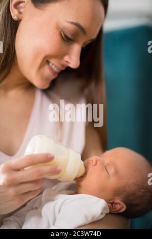 Close Up Of Loving Mother Feeding Newborn Baby Son With Bottle At Home Stock Photo