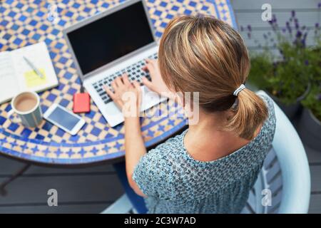 Overhead Shot Of Woman Working From Home On Laptop Outdoors In Garden During Lockdown Stock Photo