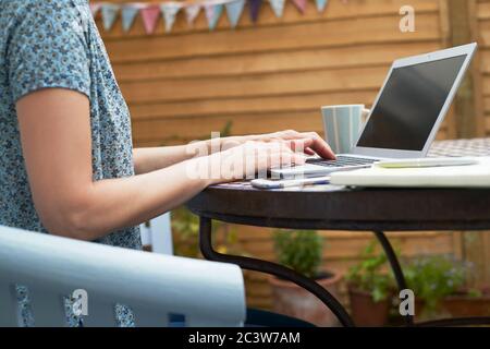 Close Up Of Woman Working From Home On Laptop Outdoors In Garden During Lockdown Stock Photo