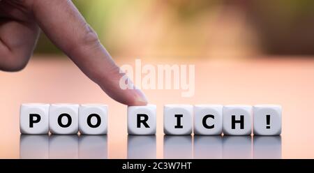 Hand moves dice and changes the word 'poor' to 'rich'. Stock Photo