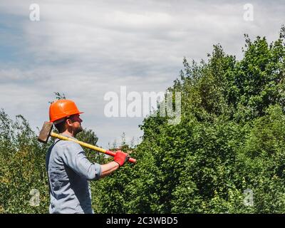Attractive man holding a sledgehammer in the park Stock Photo