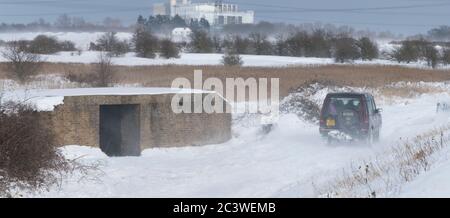 In Hoo medway a Land Rover, drives across a foot path, in between the seawall and GHQ Bunker. During a blizzard while Storm Emma batters the U.K. Stock Photo