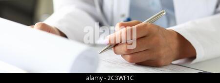 Hands of female GP making notes with silver pen Stock Photo