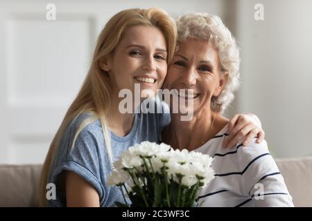 Elderly mother adult daughter sitting on couch with flowers Stock Photo