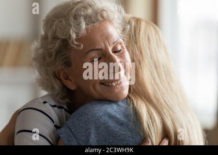 Elderly mother hugs grownup daughter enjoy moment showing attachment closeup Stock Photo