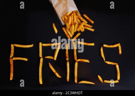 The inscription Fries. French fries on a black background. Fast food Stock Photo