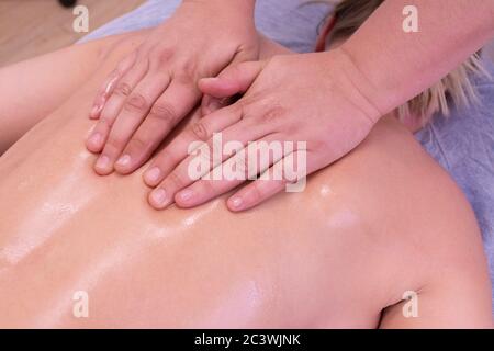 Hands of an unrecognizable woman does a physio therapeutic massage on a woman's back Stock Photo