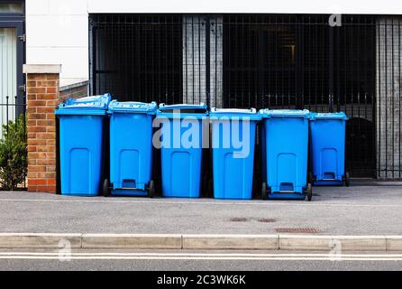 may blue wheelie bins outside a block of flats or apartments used for recycling Stock Photo