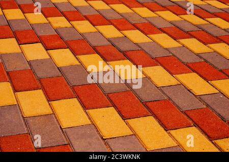 City street paved with three-color paving slabs. Sidewalk with gray, yellow and red cement rectangular tiles. Multi-colored paints of a modern city. S Stock Photo