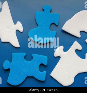 Blue background with two-color puzzle pieces. Blue and white unconnected fragments. Search and removal of excess. View from above. Stock Photo