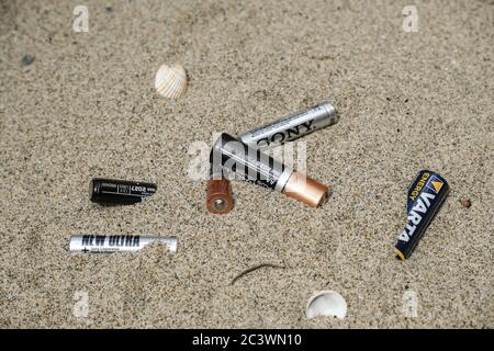 Electronic discarded battery waste on sandy sea coast ecosystem, sea pollution disease  Stock Photo