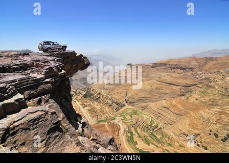 YEMEN – MARCH 13, 2010: Off-road vehicle on the edge of a steep cliff over breakaway at plateau Bokur (800m high). Extreme mountain safari is one of t Stock Photo