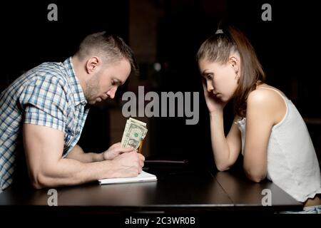 The guy counts the rest of the money in dollars and makes notes in a notebook Stock Photo