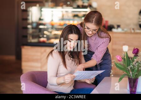 Hospitable waitress help to customer what to choose something from menu Stock Photo