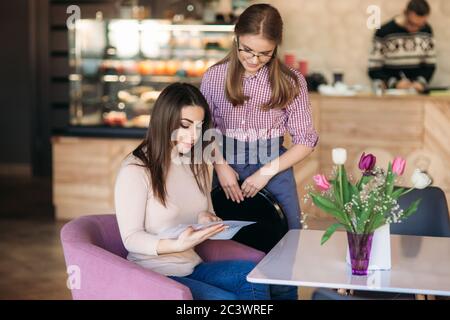 Hospitable waitress help to customer what to choose something from menu Stock Photo