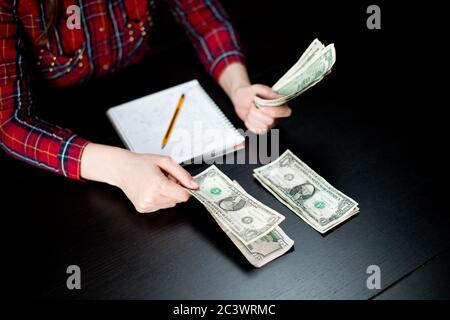 girl's hands lay out modest savings in different piles. distributes spending Stock Photo