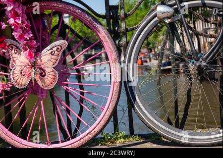Wheels of decorated pink bicycle parked on a bridge over a canal in Amsterdam, Netherlands Stock Photo