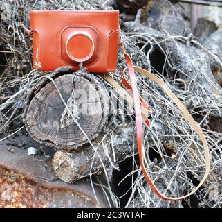 A retro camera lies on old logs and a rusty barrel. Stock Photo