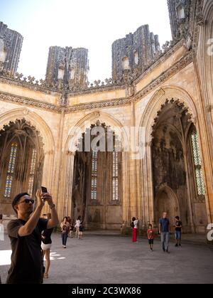 Tourists at the Unfinished Chapel with its unfinished columns and no roof was commissioned by King Duart at the Monastery of Batalha Portugal Stock Photo