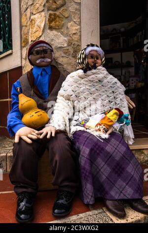 Two funny dummies man and woman sitting beside each other. Well dressed old traditional clothes with a tip money container Stock Photo