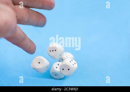 Man hand throwing five casino dices on blue background. Blurred, gaming moments in dynamic Stock Photo