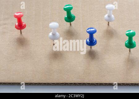 Multi colored Push Pins on White cardboard paper texture Background. Pushpins collection Stock Photo
