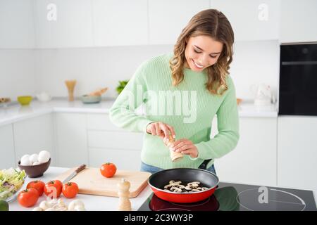 Portrait of her she nice attractive pretty focused cheerful cheery wavy-haired girl preparing delicious fresh hot domestic dish adding spice pepper in Stock Photo