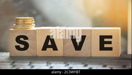 Word Save on wooden cubes on a computer keyboard with coins. Money saving and taxes saving business concept