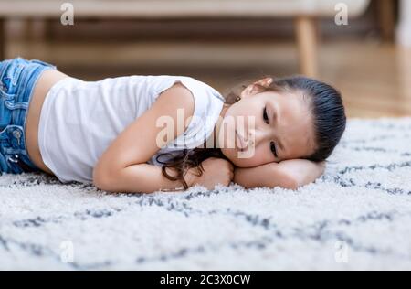 Depressed Asian Kid Girl Lying On Floor At Home Stock Photo