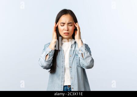 Lifestyle, people emotions and beauty concept. Troubled and distressed young asian woman feeling dizzy, close eyes and rub temples, have headache or Stock Photo