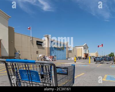 Toronto  Canada, June 9, 2020; a Canadian Walmart store with Canadian flags flying seen through a shopping cart in a mall parking lot Stock Photo