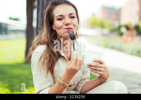 Happy young woman enjoy eating delicious salad outdoor in park Stock Photo