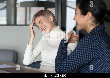 Diverse colleagues laughing over joke during workday break Stock Photo