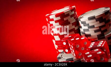 Casino games and gambling concept with stacked poker chips and red dice used in the game of craps. There are two white stacks and one red stack agains Stock Photo