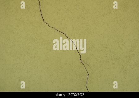 Large crack on a green cemented painted wall. Wallpaper, background Stock Photo