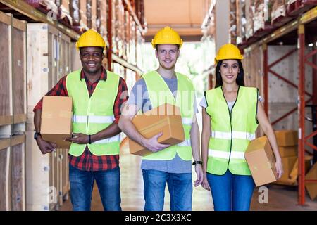 Portrait of caucasian white and african black warehouse workers hold cardboard box packaging in warehouse distribution center environment. Using in bu Stock Photo