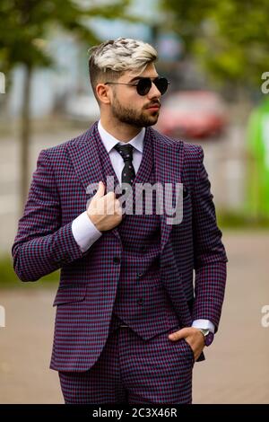 man in glasses and violet luxery three-piece suit, bow tie posing on the street Stock Photo