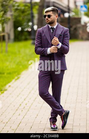 young attractive executive businessman wearing on violet luxery three-piece suit standing outdoors on street dressing for success Stock Photo
