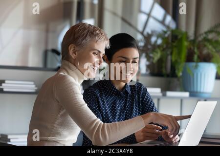 Multiethnic female colleague international department members working together using laptop Stock Photo