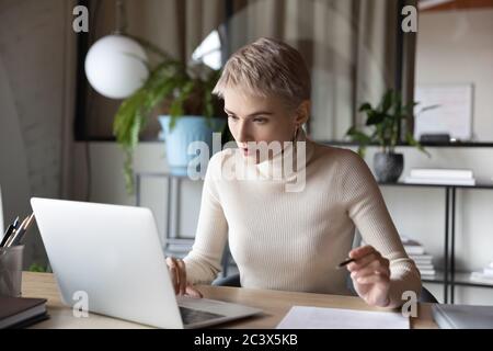 Focused businesswoman working on research sit at desk use laptop Stock Photo