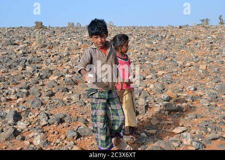 Socotra, Yemen - March 8, 2010: Young boy and his little sister sale a box with dragon blood trees wood resin at Socotra island. Children grow up in t Stock Photo