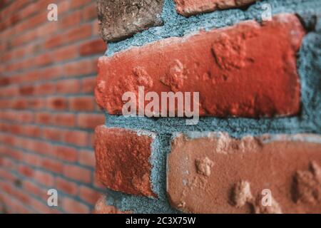 Side angle of a red brick wall corner. Close up view of cracked weathered brickwork material. Modern interior design, unique perspective. Loft like Stock Photo